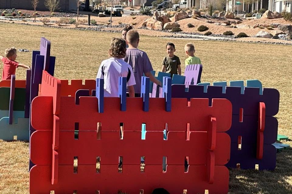 Children playing on an interlocking foam block castle on a lawn
