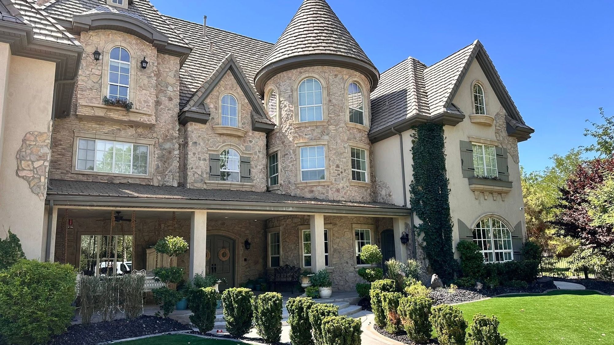 A large custom home with stone veneer and foam window surrounds, trim, and corbels