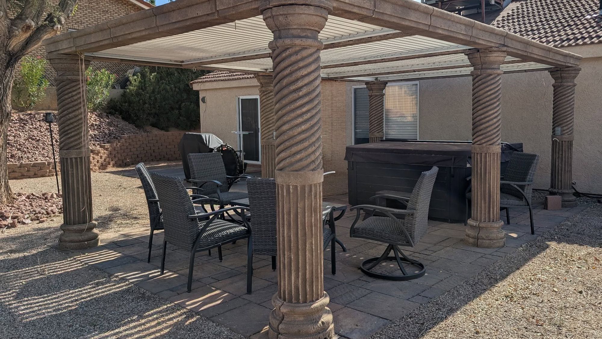 A backyard pergola built on spiral fluted foam columns over a paver patio